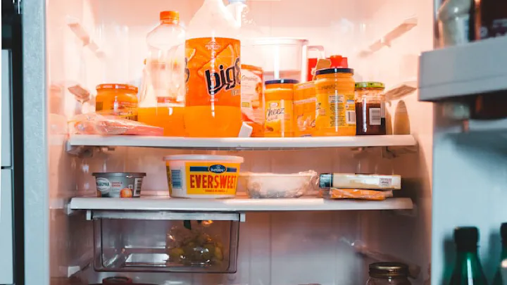 A stocked refrigerator interior with drinks, snacks, and various groceries visible on multiple shelves.