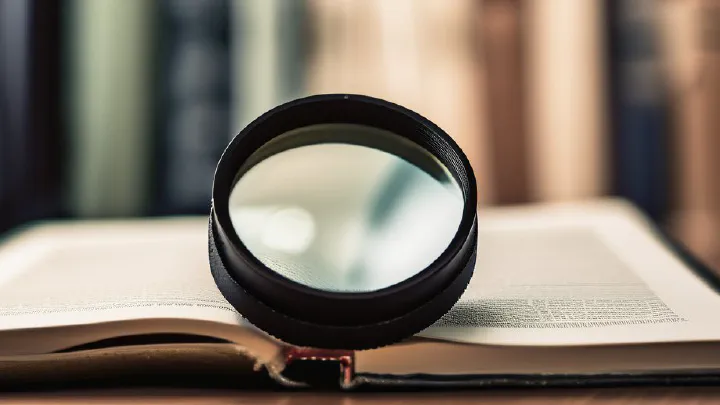 A magnifying glass resting on an open book in a library